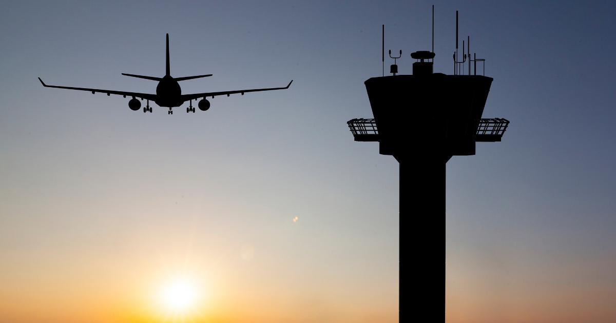 Lentokone ilmassa ja lennonjohtotorni ilta-auringossa (Kuva: Shutterstock)