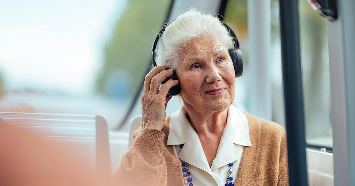 Äldre kvinna reser på robotbuss, hörlurar med öron (Bild: Mika Pakarinen, Keksi / KM)
