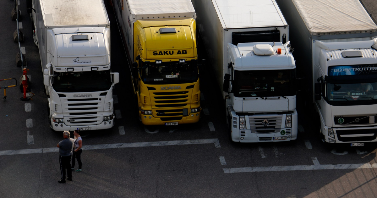 Lastbilar i hamnen, två personer som står bredvid lastbilarna. (Foto: Shutterstock)